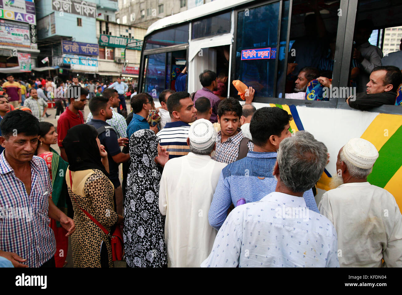 Bangladeshi people try to ride in of an overcrowded bus to travel home ...