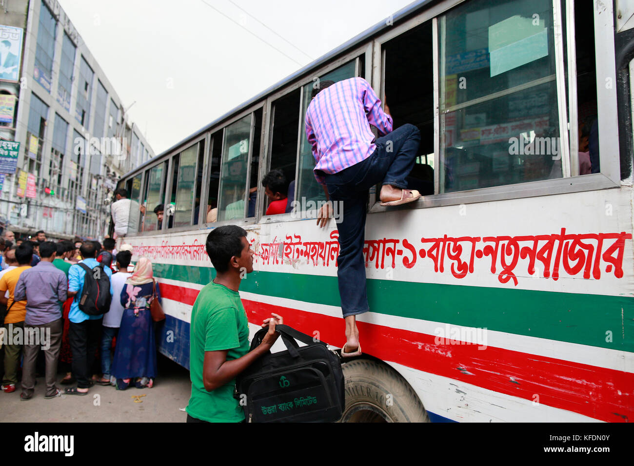 Bangladeshi people try to ride in of an overcrowded bus to travel home, as others wait for transport ahead of Iftar, in Dhaka, Bangladesh Stock Photo