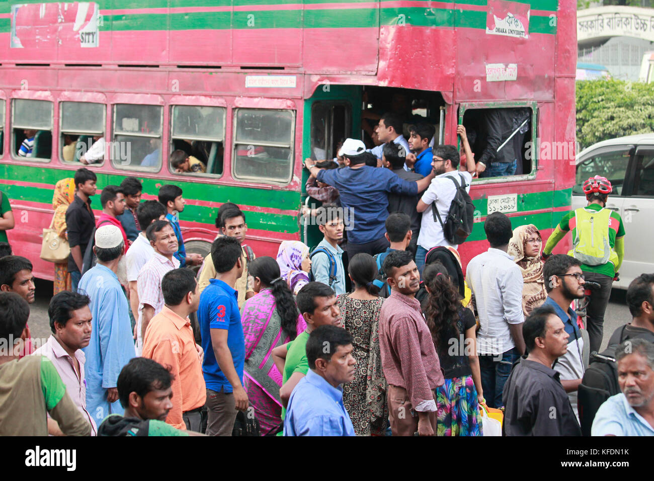 Bangladeshi people try to ride in of an overcrowded bus to travel home, as others wait for transport ahead of Iftar, in Dhaka, Bangladesh Stock Photo