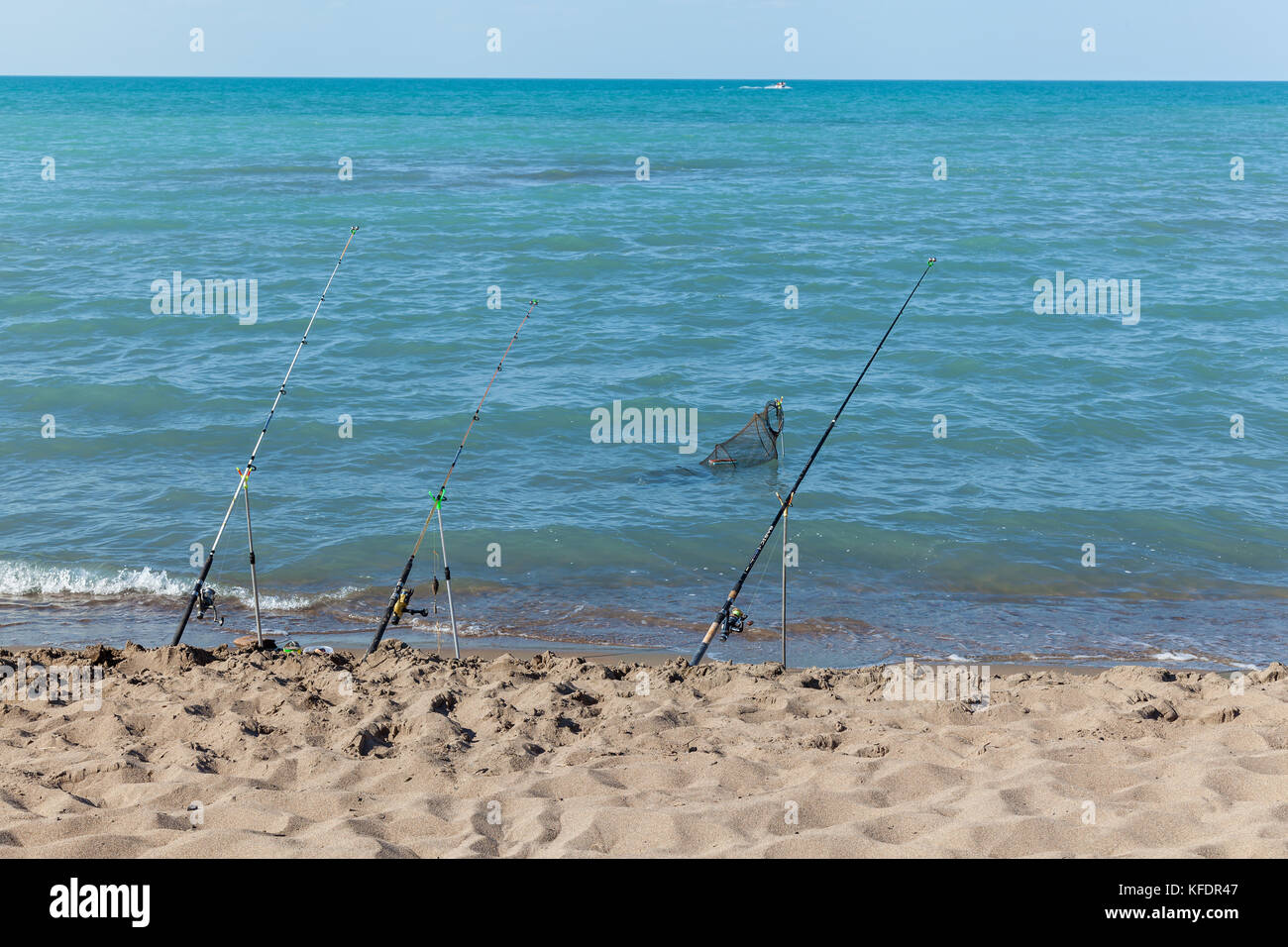 Fishing rods stand on the sandy beach Fixed fishing rod set up on a beach  near the surf on the incoming tide. Blue sky with clouds, turquoise sea  Stock Photo - Alamy