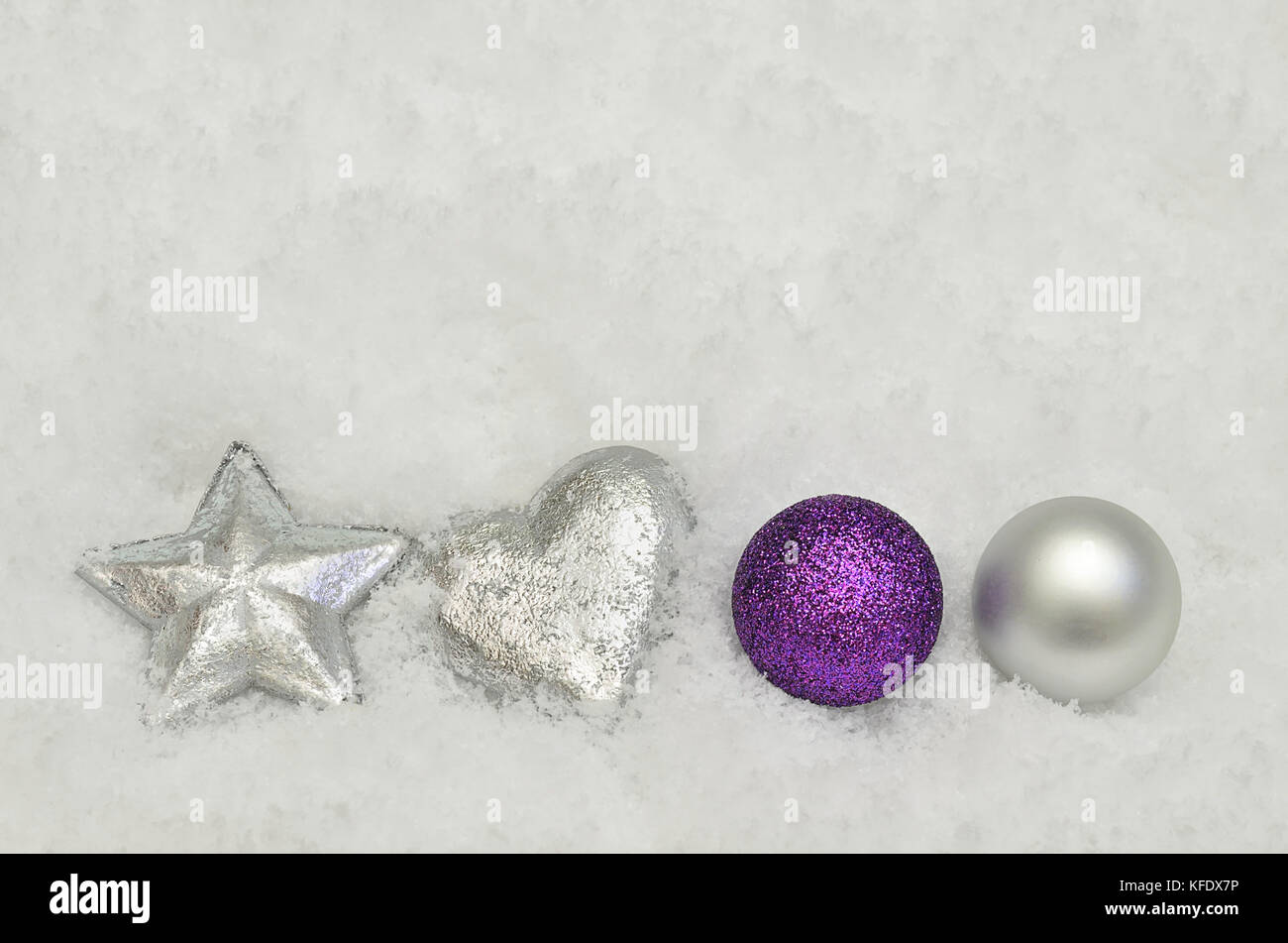 close up of silver and purple Christmas tree decorations on snow background Stock Photo