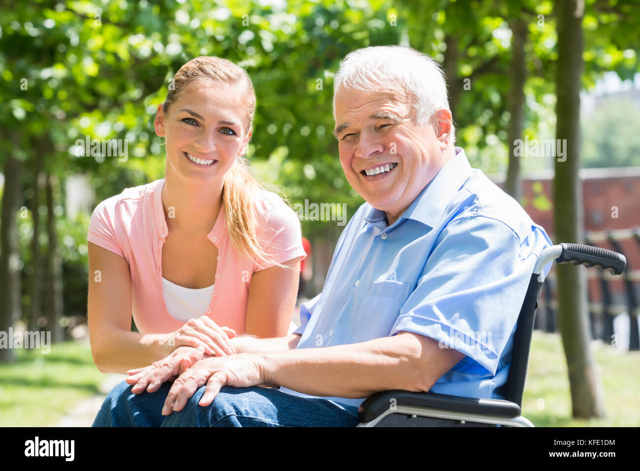 Portrait Of A Smiling Young Woman With Her Disabled Father On Wheelchair Stock Photo