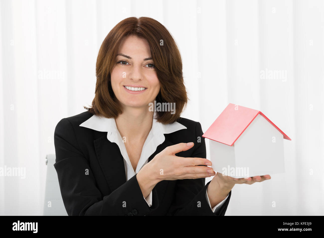 Happy Businesswoman Holding House Model In Office Stock Photo - Alamy