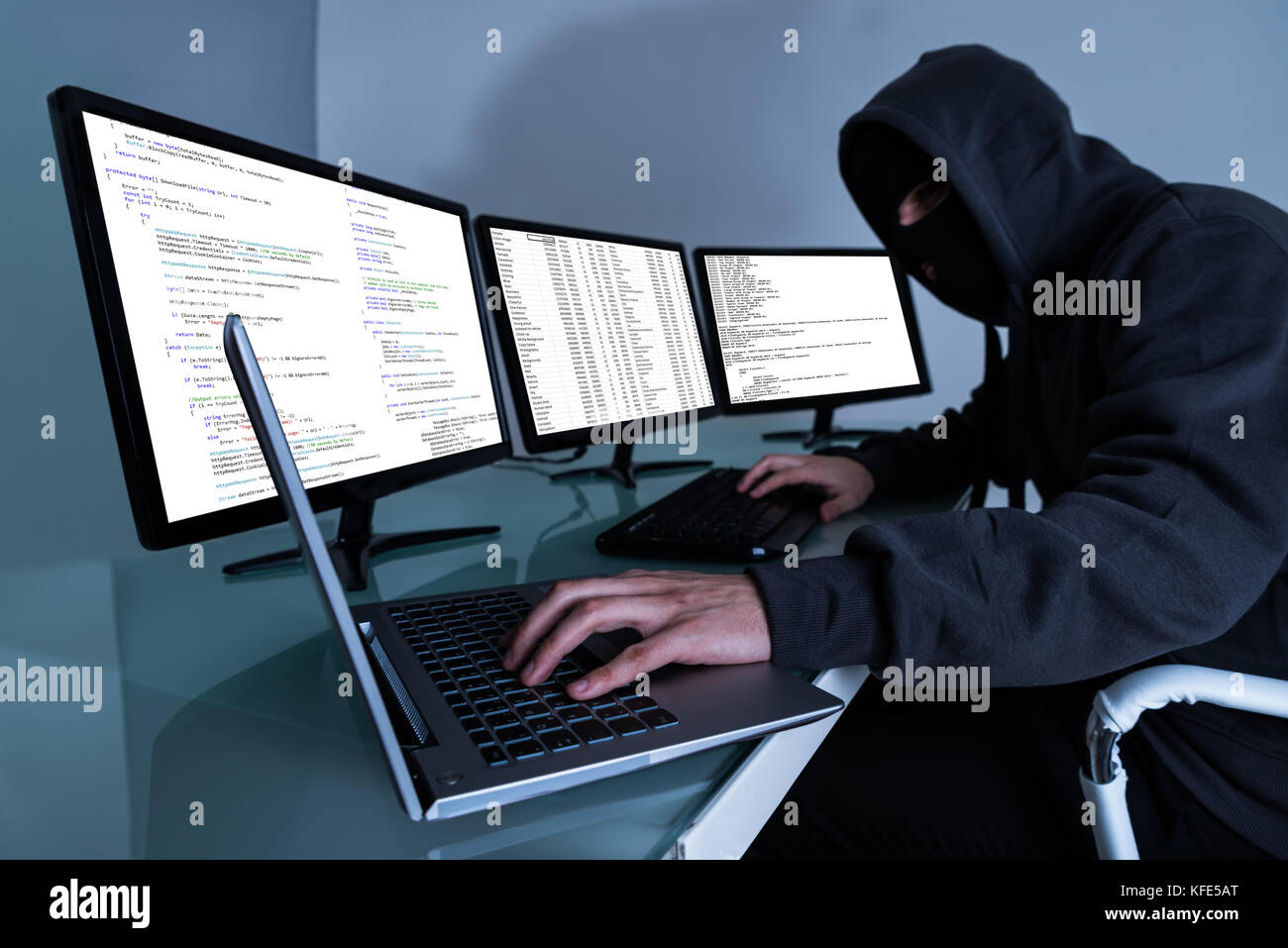 Hacker Stealing Data On Multiple Computers And Laptop Stock Photo