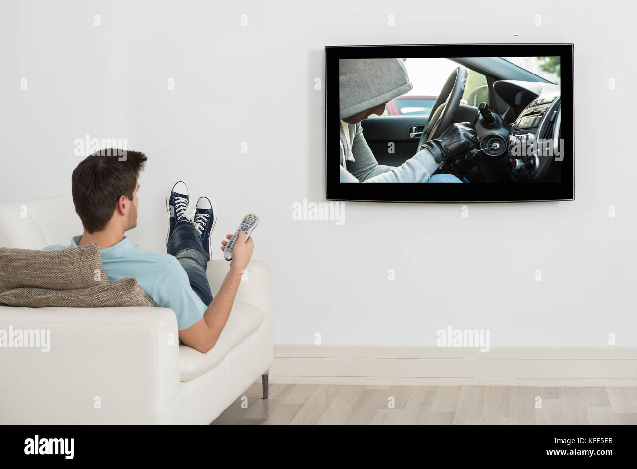 Young Man Lying On Couch Watching Movie On Television Stock Photo