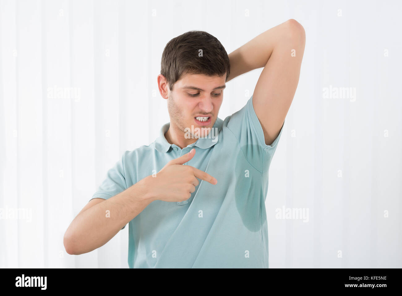 Young Man With Hyperhidrosis Pointing To A Sweat Armpit Stock Photo