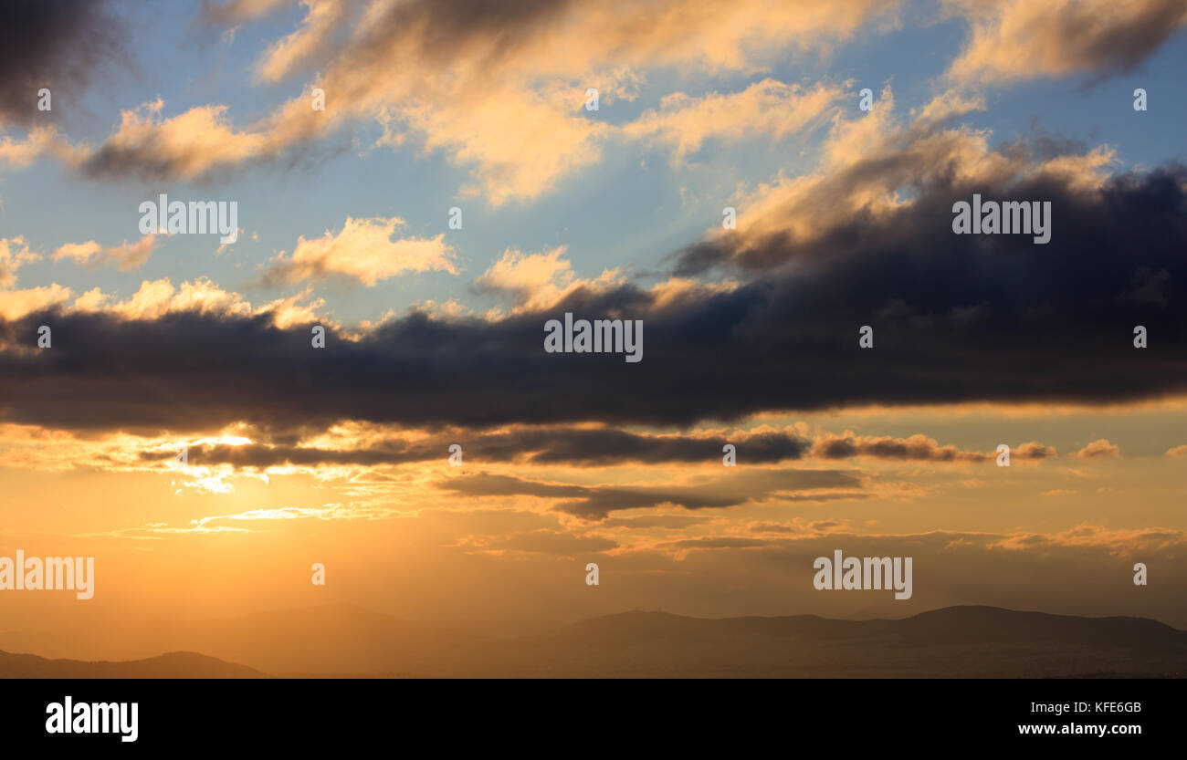 Beautiful sunset on colorful sky. Gold sun lightens the clouds over ...