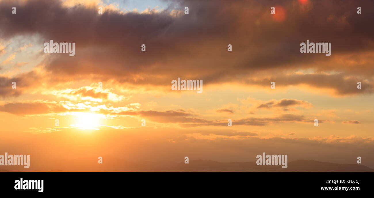 Beautiful sunset on colorful sky. Gold sun lightens the clouds over ...
