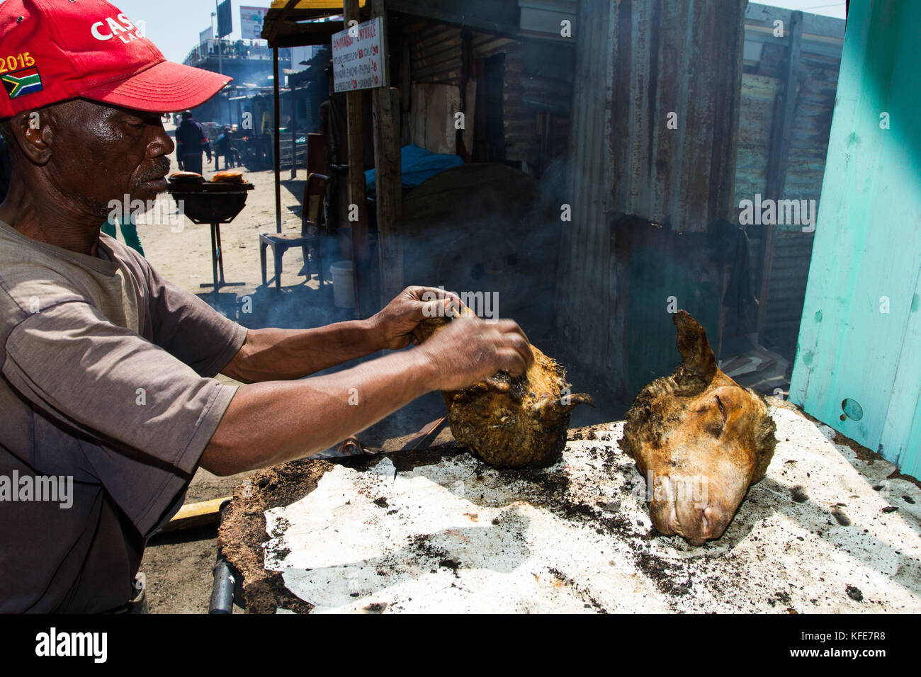 Street vendor cooking 'smiley' sheep head in Khayelitsha township, Cape Town, South Africa Stock Photo