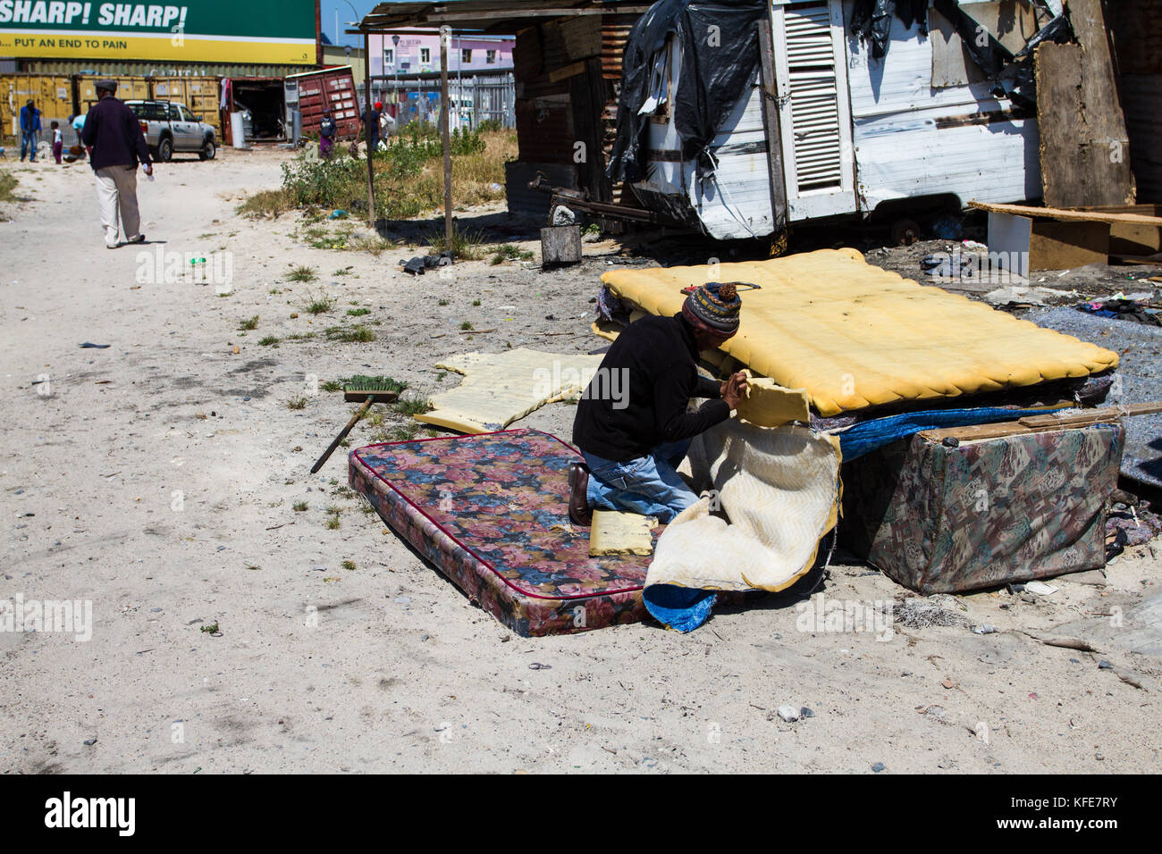 An entrepreneur fixes used bed mattresses for resale in Khayelitsha township, Cape Town, South Africa. Stock Photo