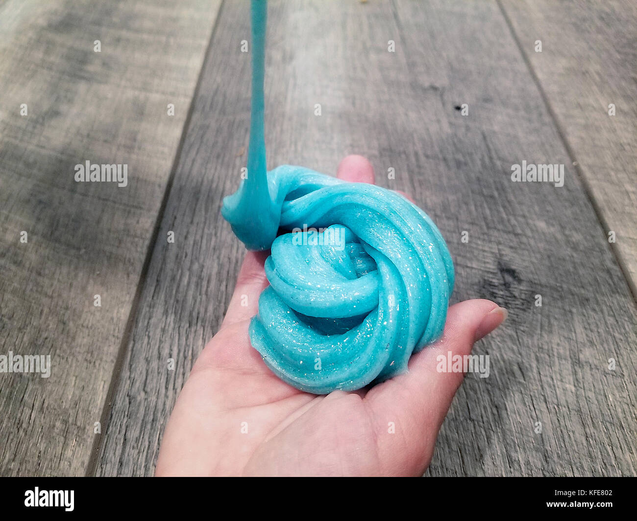 glob of turquoise glittery slime in young girl's hand Stock Photo
