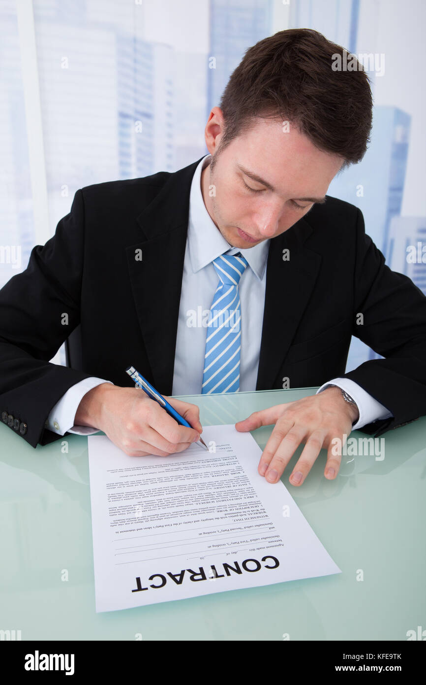 Young businessman signing contract paper at office desk Stock Photo