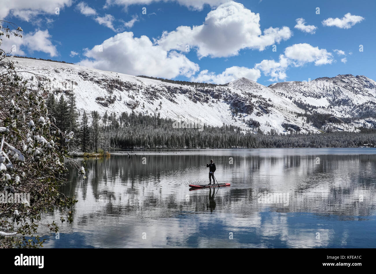 Man on SUP paddles in Lake Mary in the Mammoth Lakes Basin in Mammoth Lakes in the Eastern Sierra in California Stock Photo