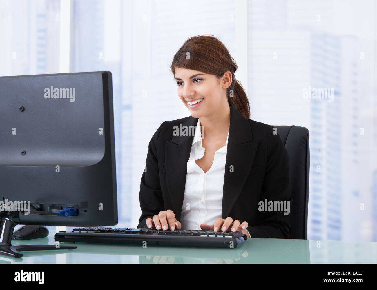 Young businesswoman using computer at office desk Stock Photo - Alamy