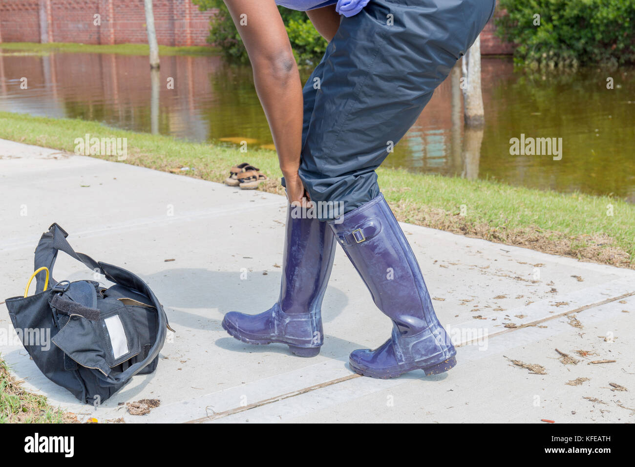 Resident puts on waterproof boots and prepares for walking in high waters Stock Photo