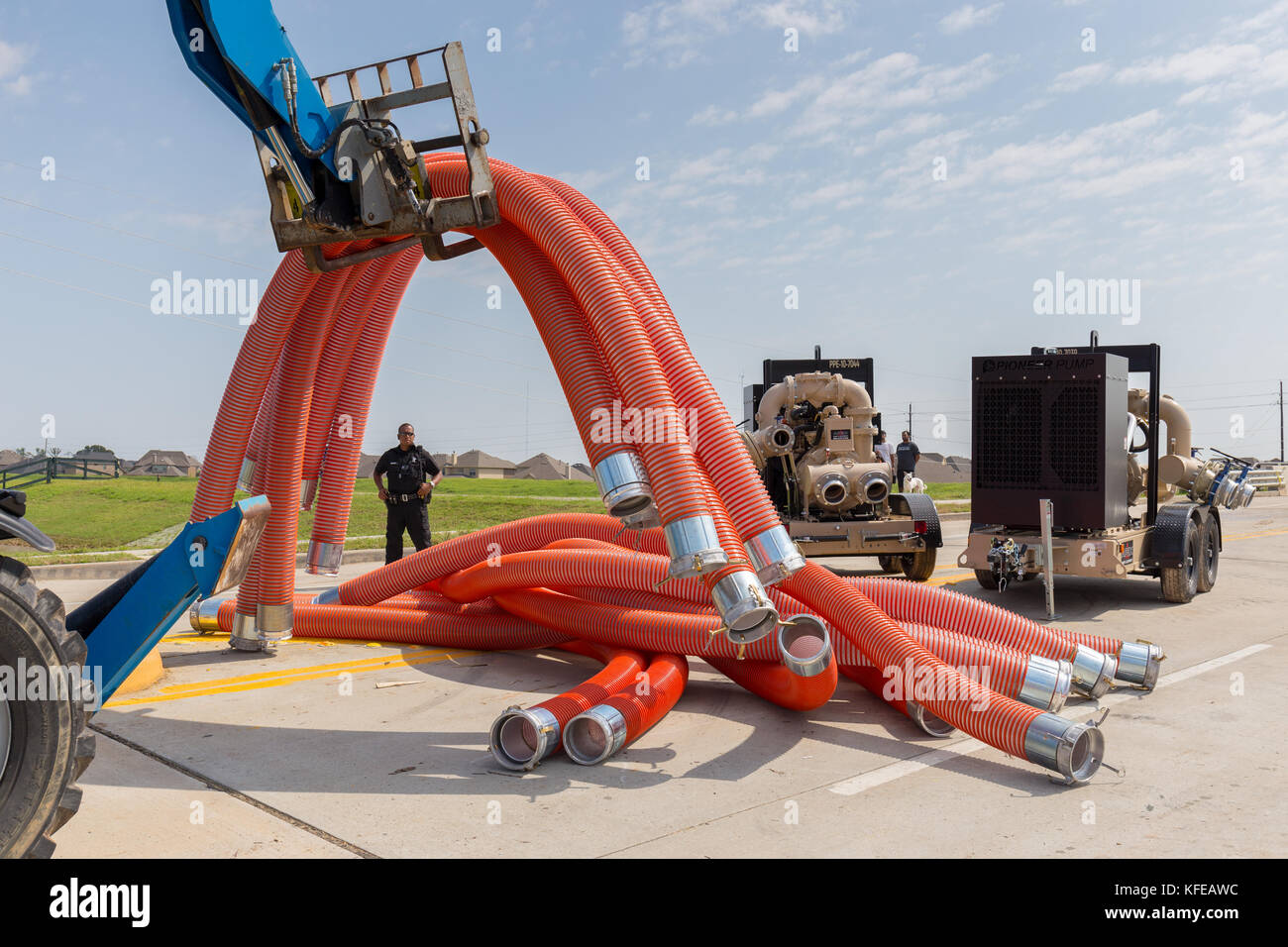 Business equipment - A fork lift loads flexible hose pipes used for pumping flood water into a dump truck Stock Photo
