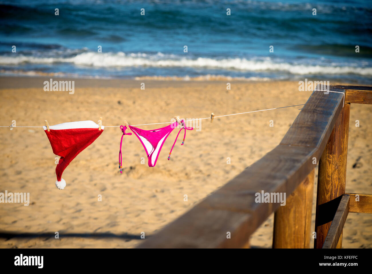 Bikini tanga and Santa hat drying on a sunny beach, a seasonal getaway concept Stock Photo