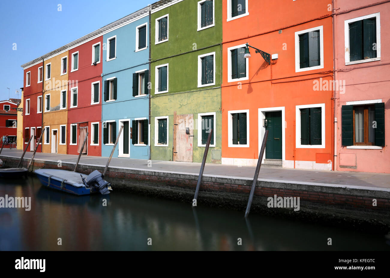 canal and the colorful houses of the BURANO island near Venice with moving boats due to the long exposure time Stock Photo