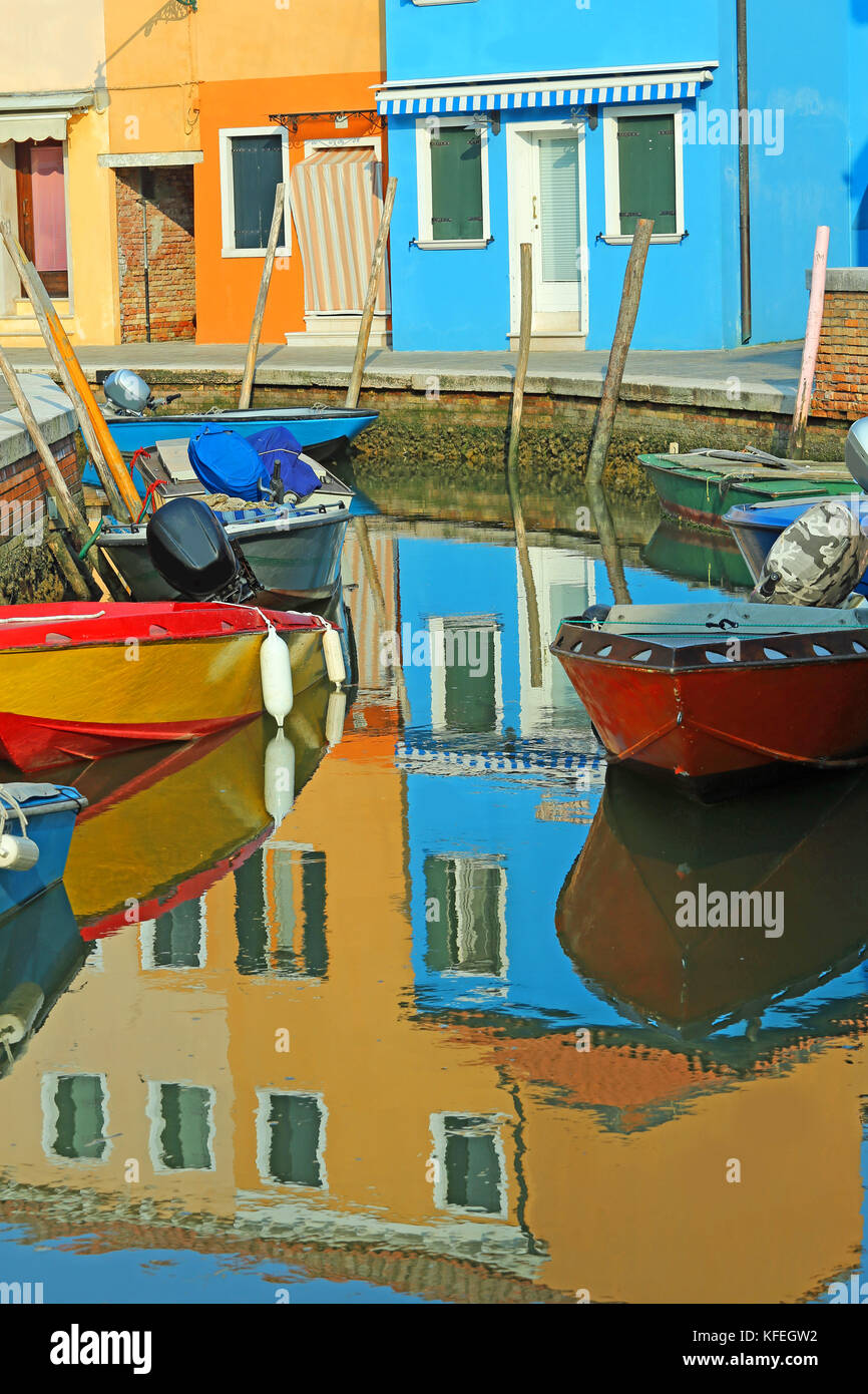 reflection in the water of navigable canal of colored house and boats in BURANO island near Venice in Italy Stock Photo