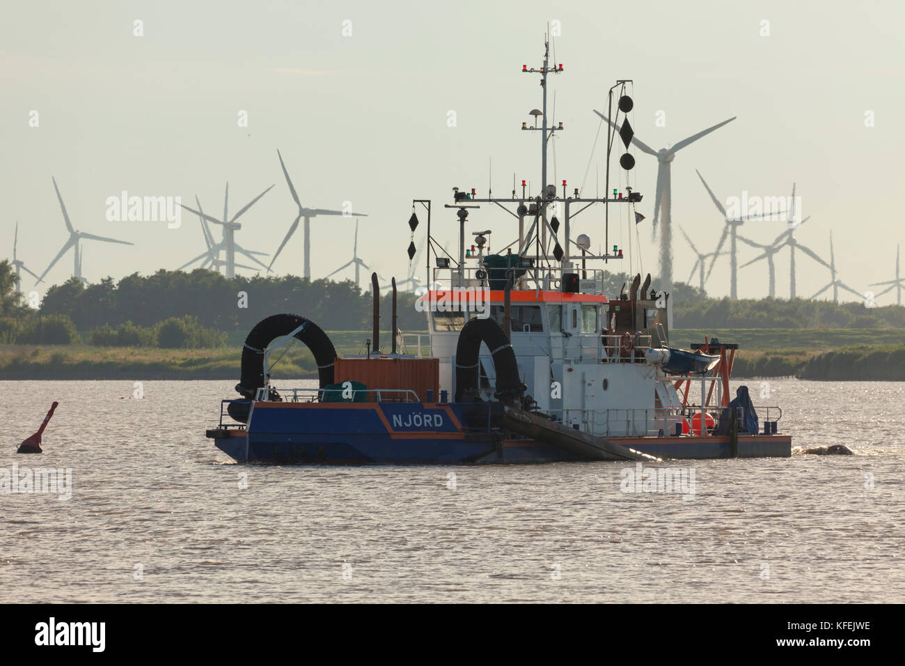 Dredger „Njörd“ on Elbe river, wind turbines in background Stock Photo