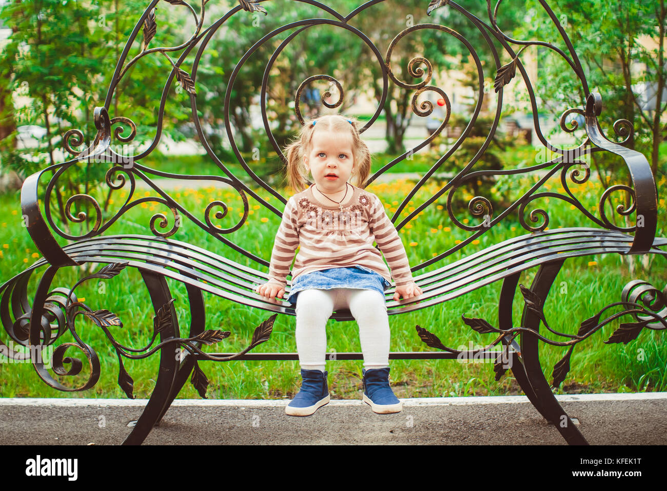 Small girl sitting on the bench in park Stock Photo - Alamy