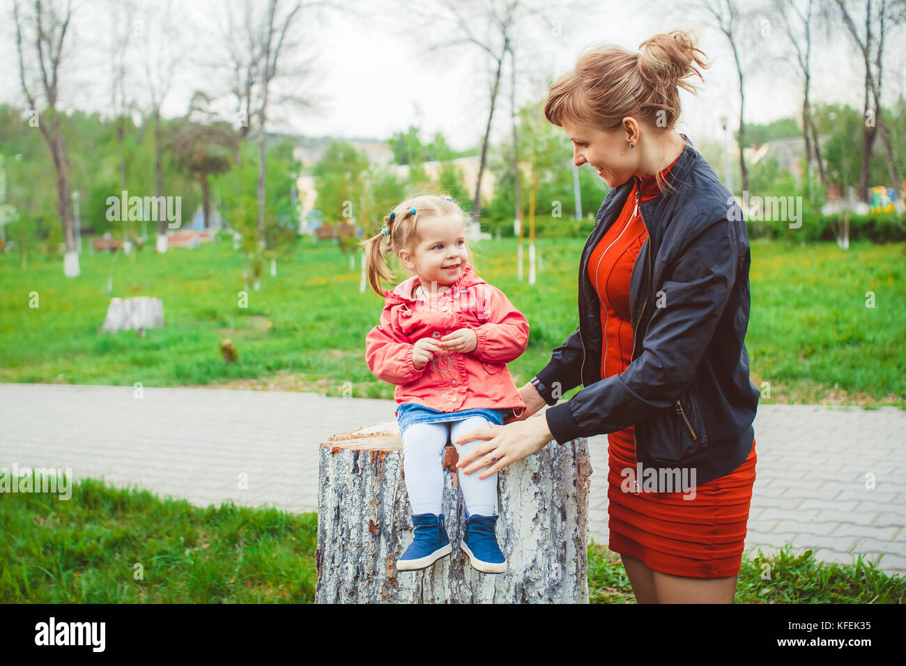 little girl sitting on a stump in the summer garden Stock Photo - Alamy