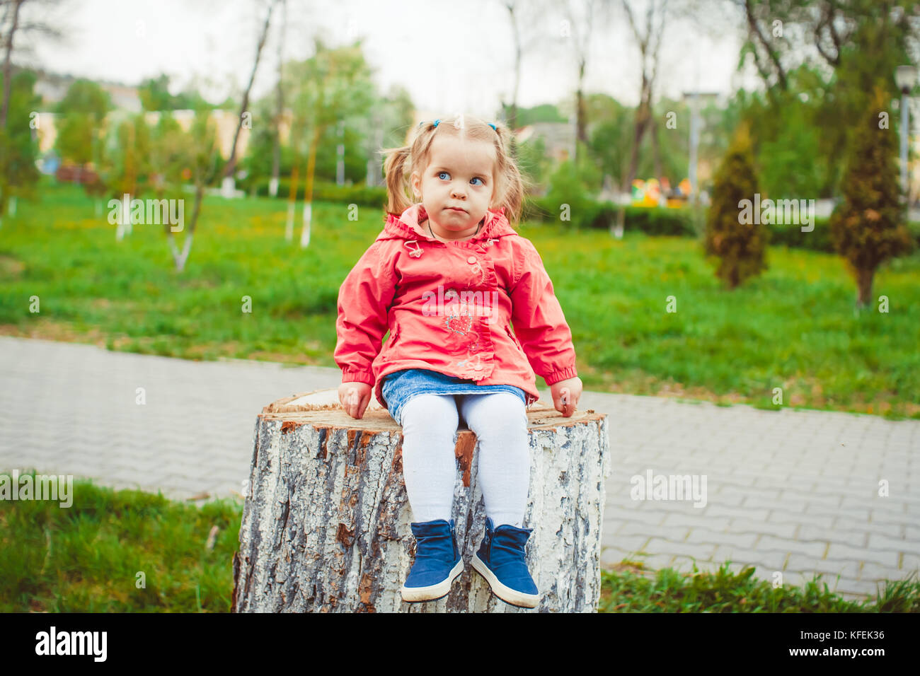 little girl sitting on a stump in the summer garden Stock Photo - Alamy