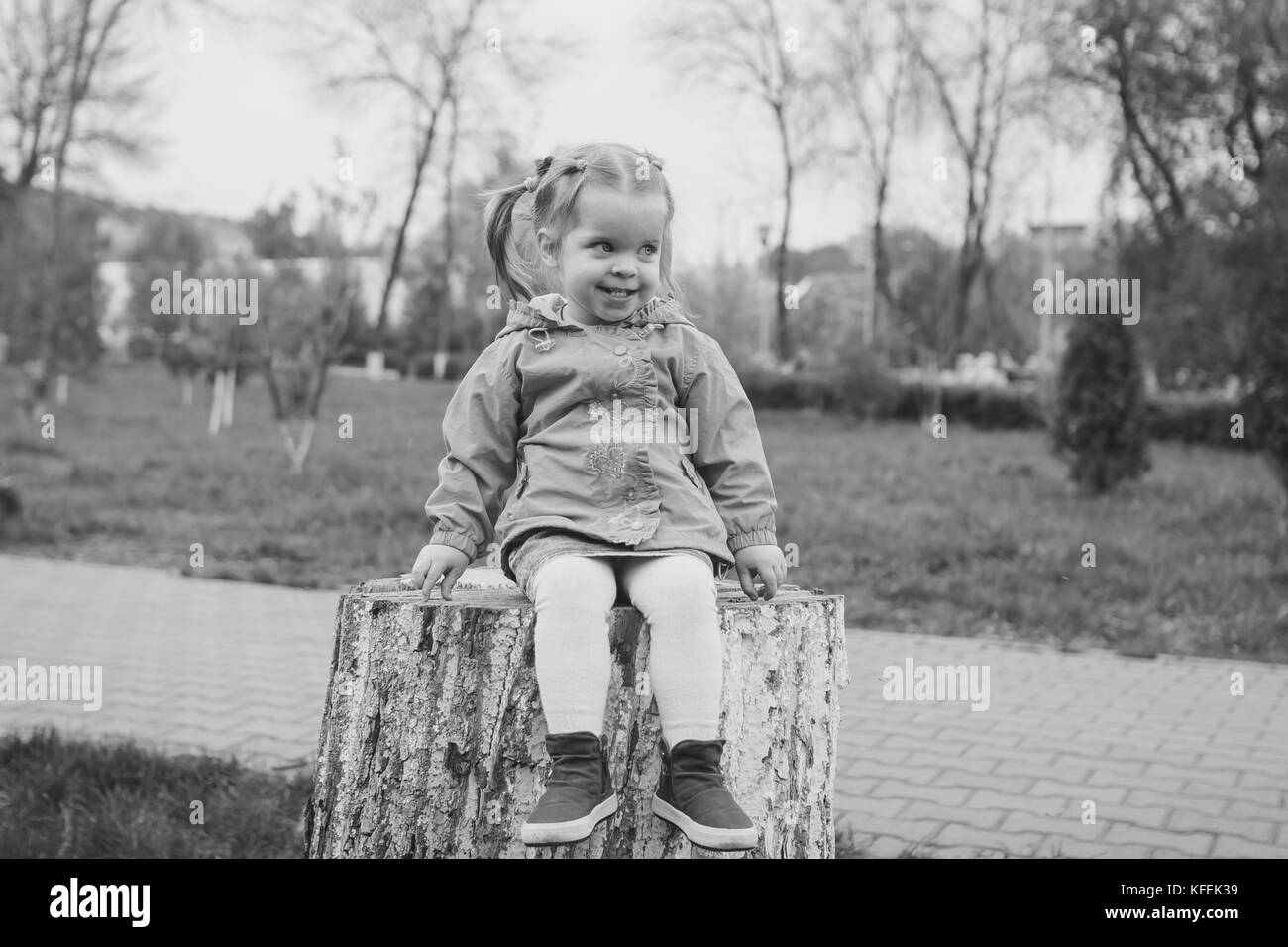 little girl sitting on a stump in the summer garden Stock Photo - Alamy