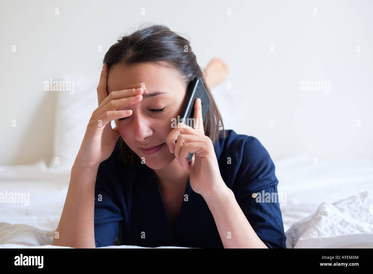 Sad woman making a phone call on the bed Stock Photo