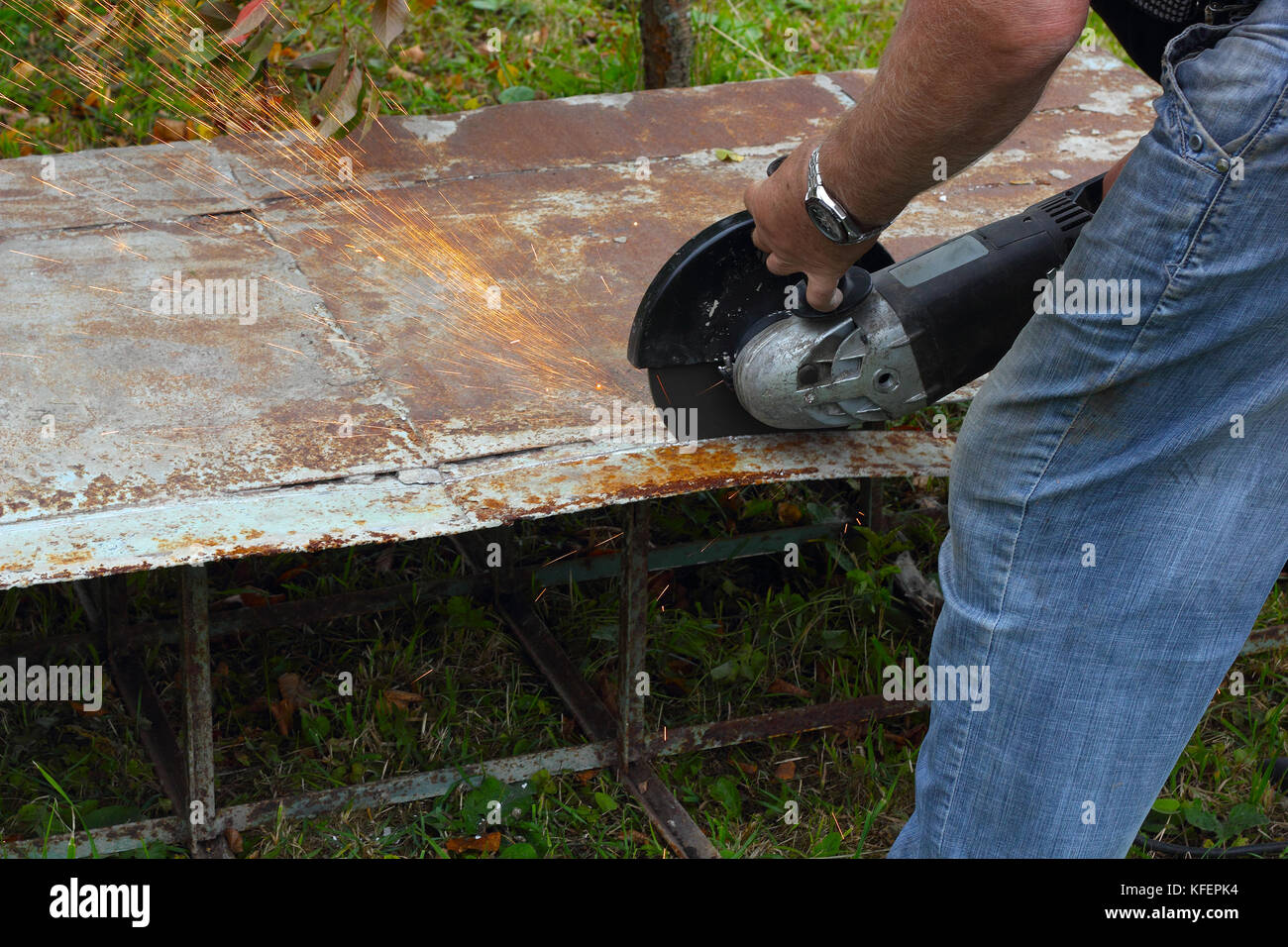 Worker cuts metal sheet by angle grinder photo Stock Photo