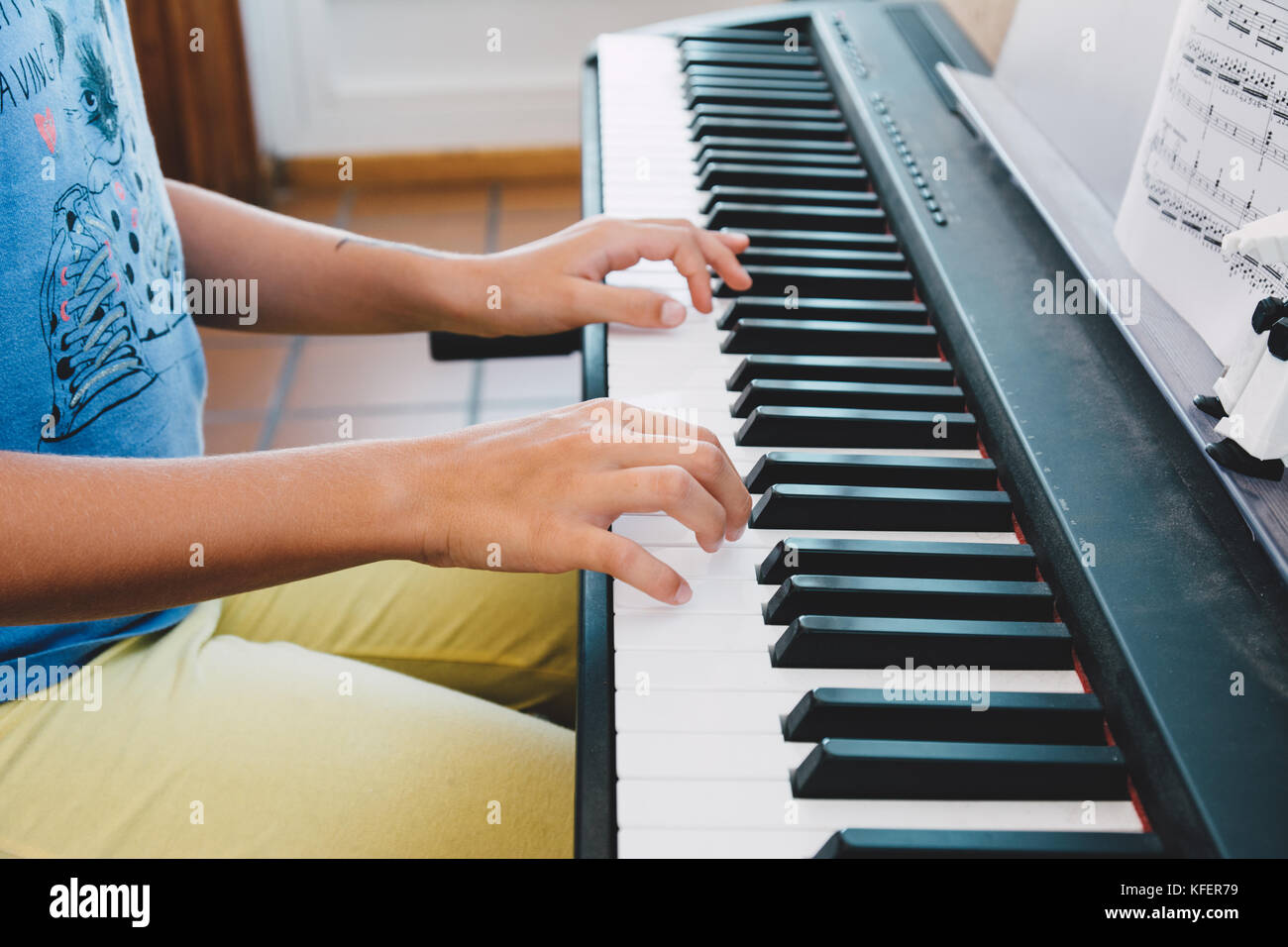 9-year-old girl playing the electric piano in front of the score book Stock Photo