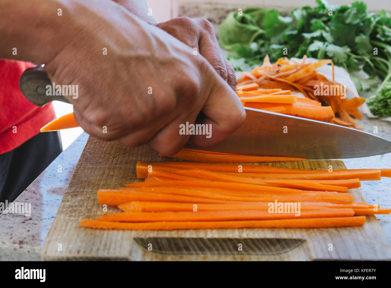 man's hands, cut carrot julienne style, in the kitchen Stock Photo
