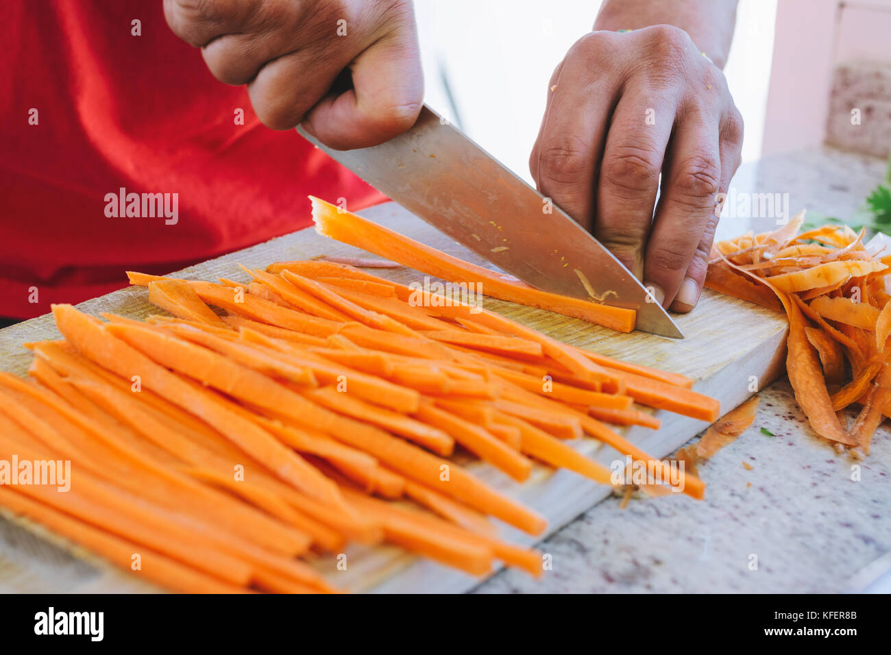man cooking, cut carrot julienne style, in the kitchen Stock Photo