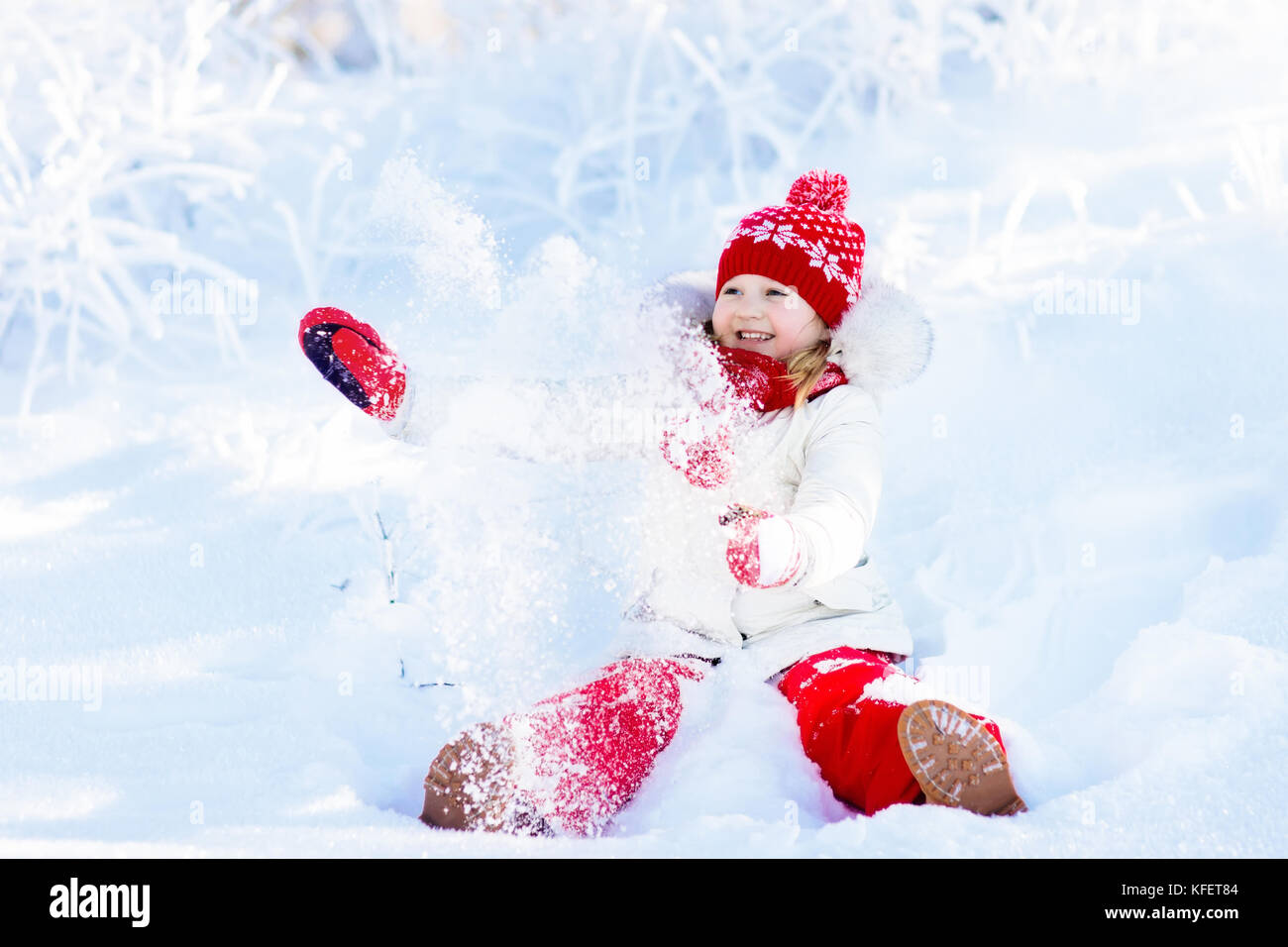 Child playing with snow in winter. Little girl in colorful jacket and ...