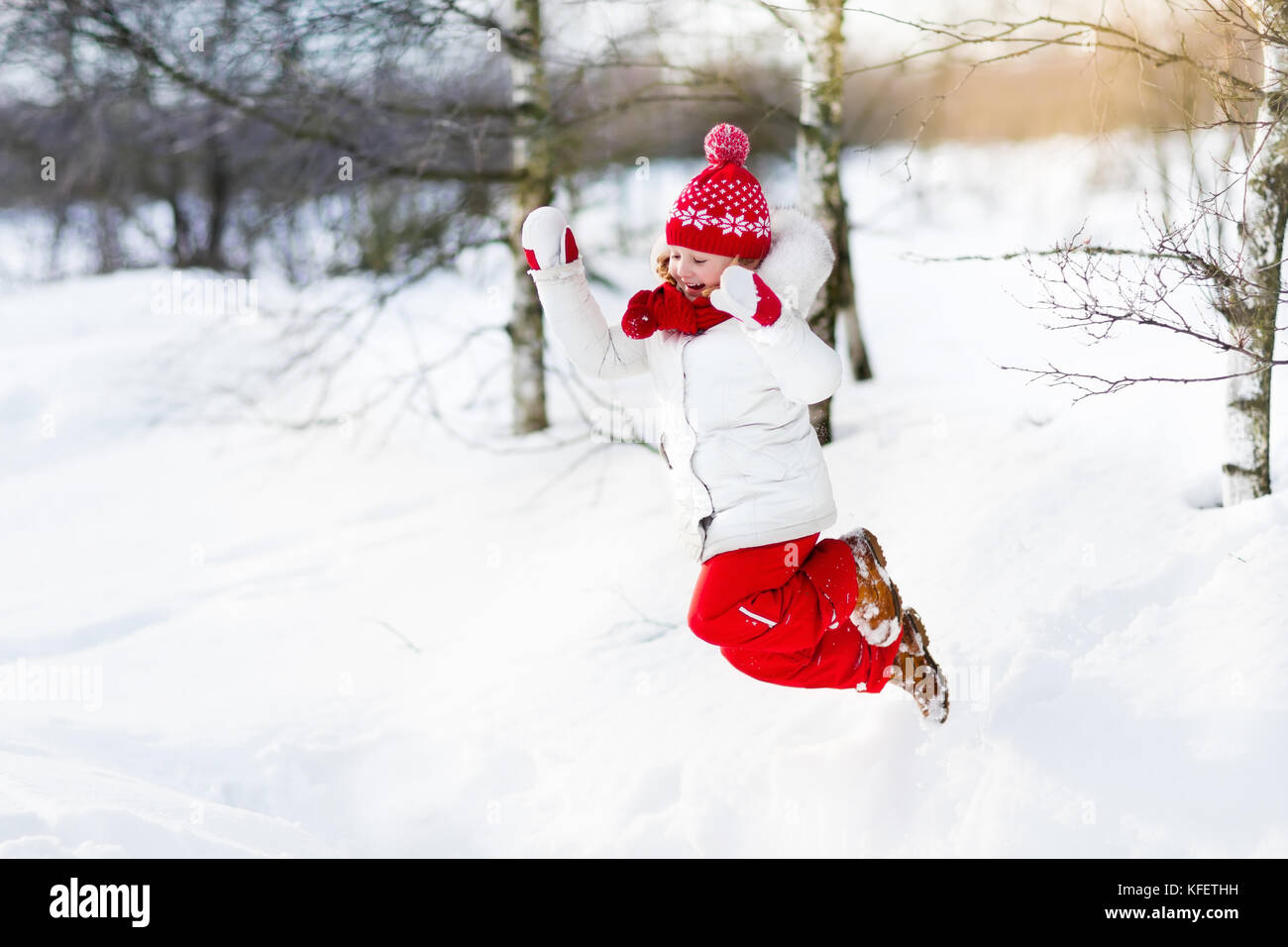 Child playing with snow in winter. Little girl in colorful jacket and ...