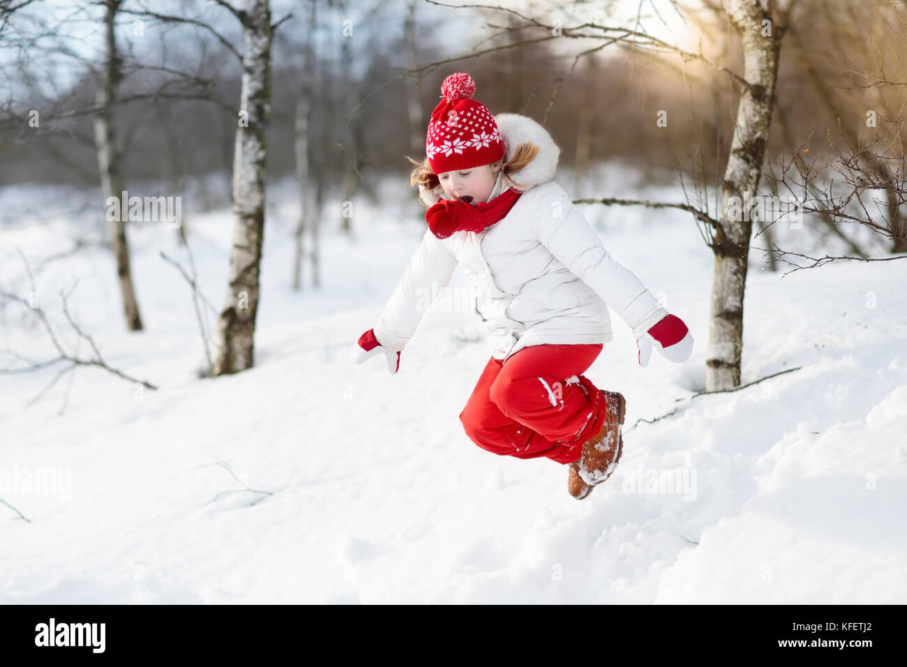Child playing with snow in winter. Little girl in colorful jacket and ...