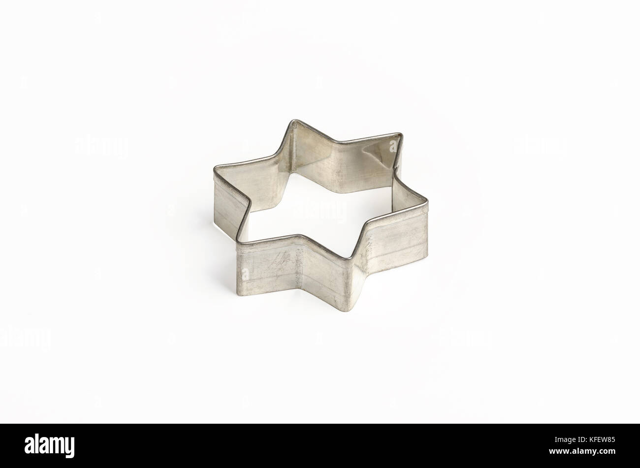 Star shaped Christmas cookie cutter over white. Tin biscuit cutter, a tool to cut cookie dough in particular shape and to make cutouts. Stock Photo