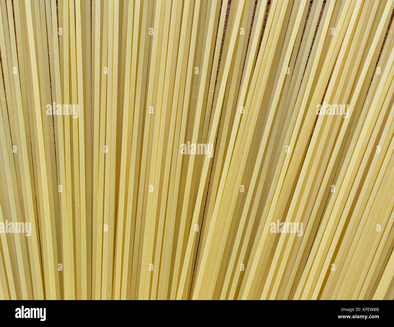Spaghetti uncooked pasta on top of a light brown wooden surface, with lots of wheat flour sprinkled on top and around Stock Photo