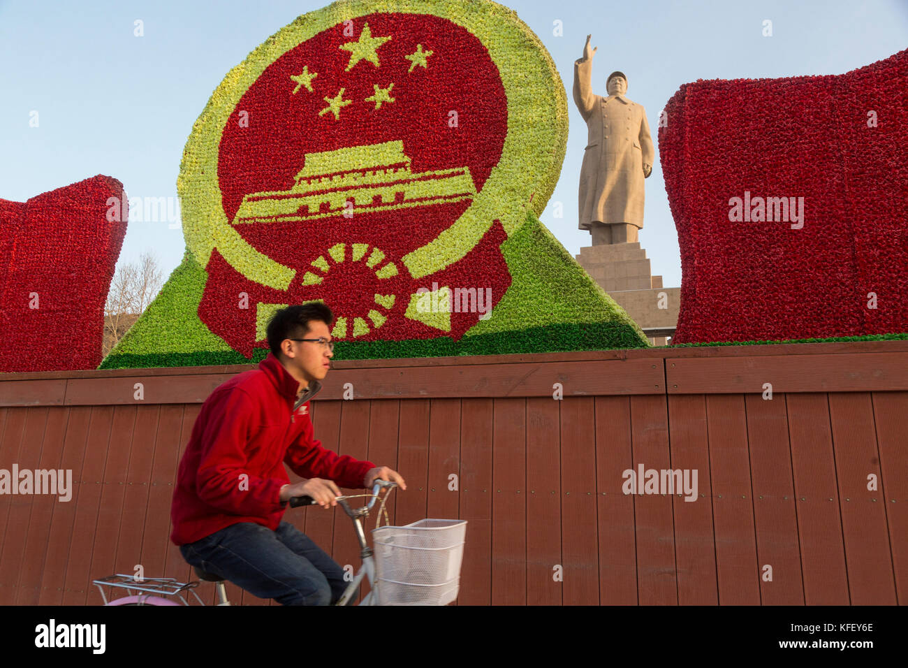 A Chinese man rides a bicycle past a huge monument to Mao Zedong in Kashgar city, Xinjiang Uygur Autonomous Region of China Stock Photo