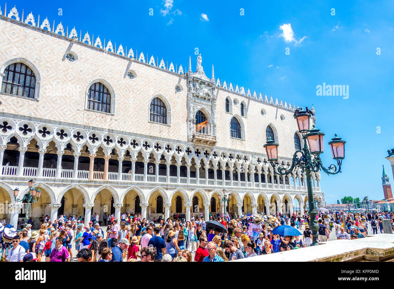 Tourists admire the Doge's Palace (Palazzo Ducale) facade viewed from St Mark's Square (Piazzetta di San Marco) in Venice, Italy Stock Photo