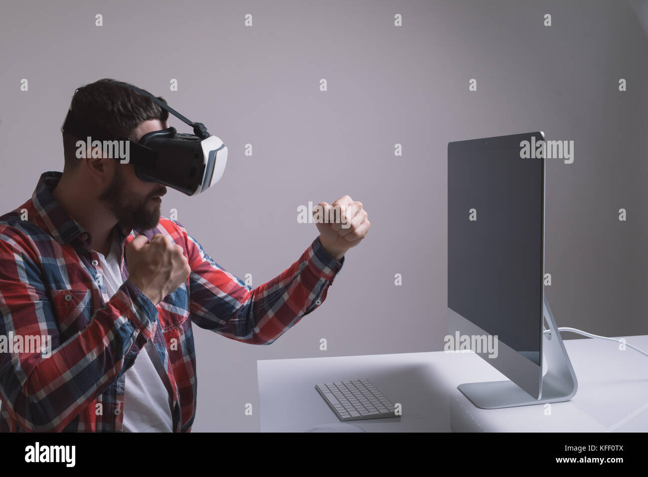 Man in helmet virtual reality plays game at desk. Man uses VR