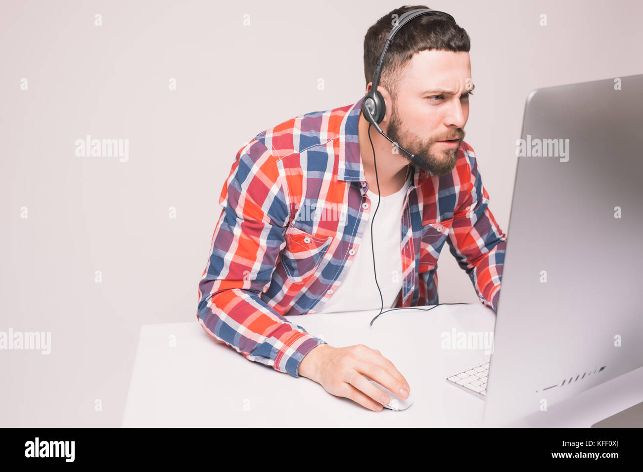 Smiling casual young man with headset using computer in a bright office Stock Photo