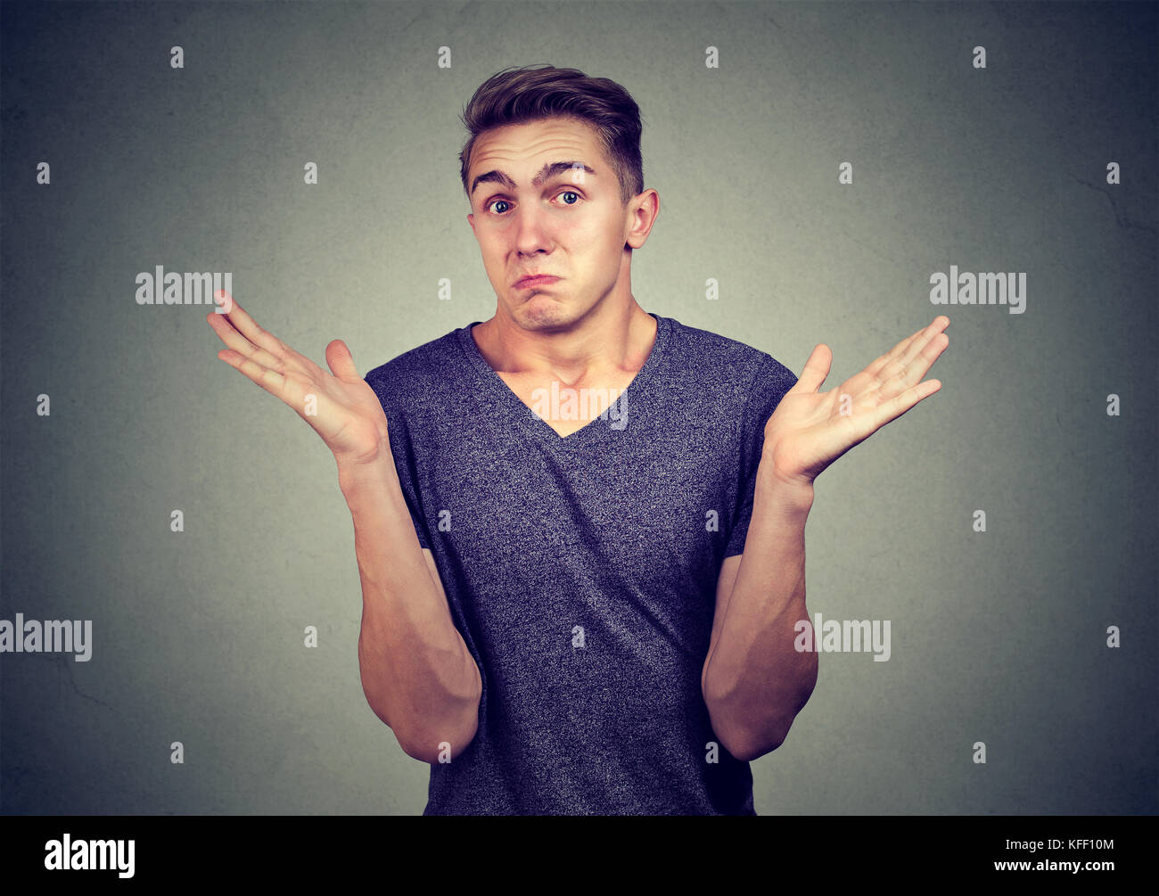 Closeup portrait young man shrugging shoulders isolated on gray wall background. Body language Stock Photo