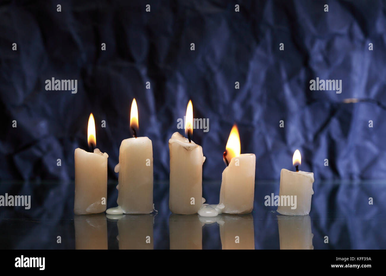 Premium Photo  Power outages concept, three candles, one with flame and  two reserve, on the desk, dark background