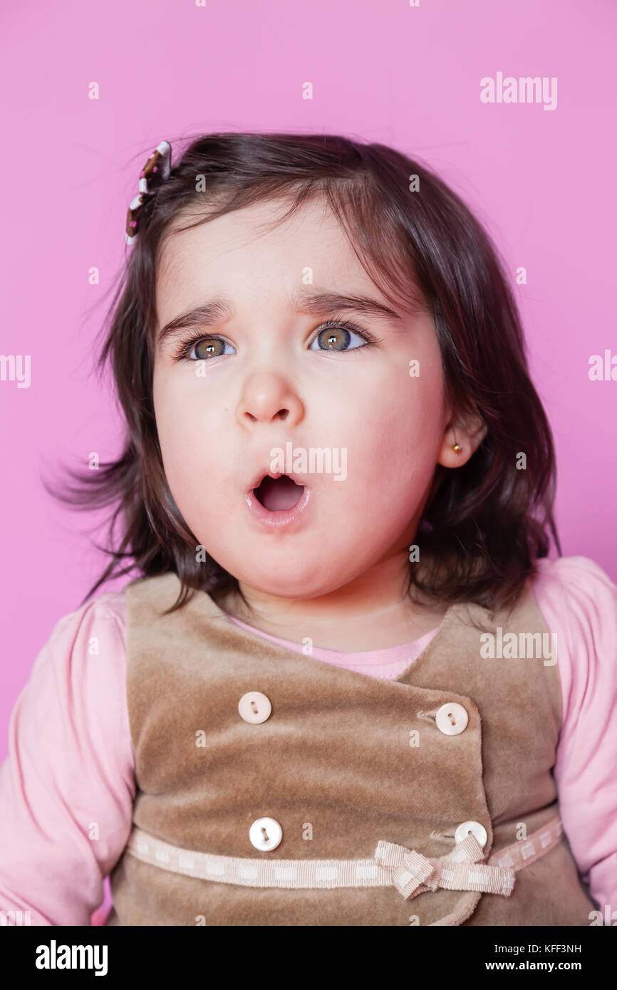 Cute, pretty and happy baby toddler girl shocked or surprised with open round mouth. 18 or eighteen months old / surprise shock scared, open mouth Stock Photo
