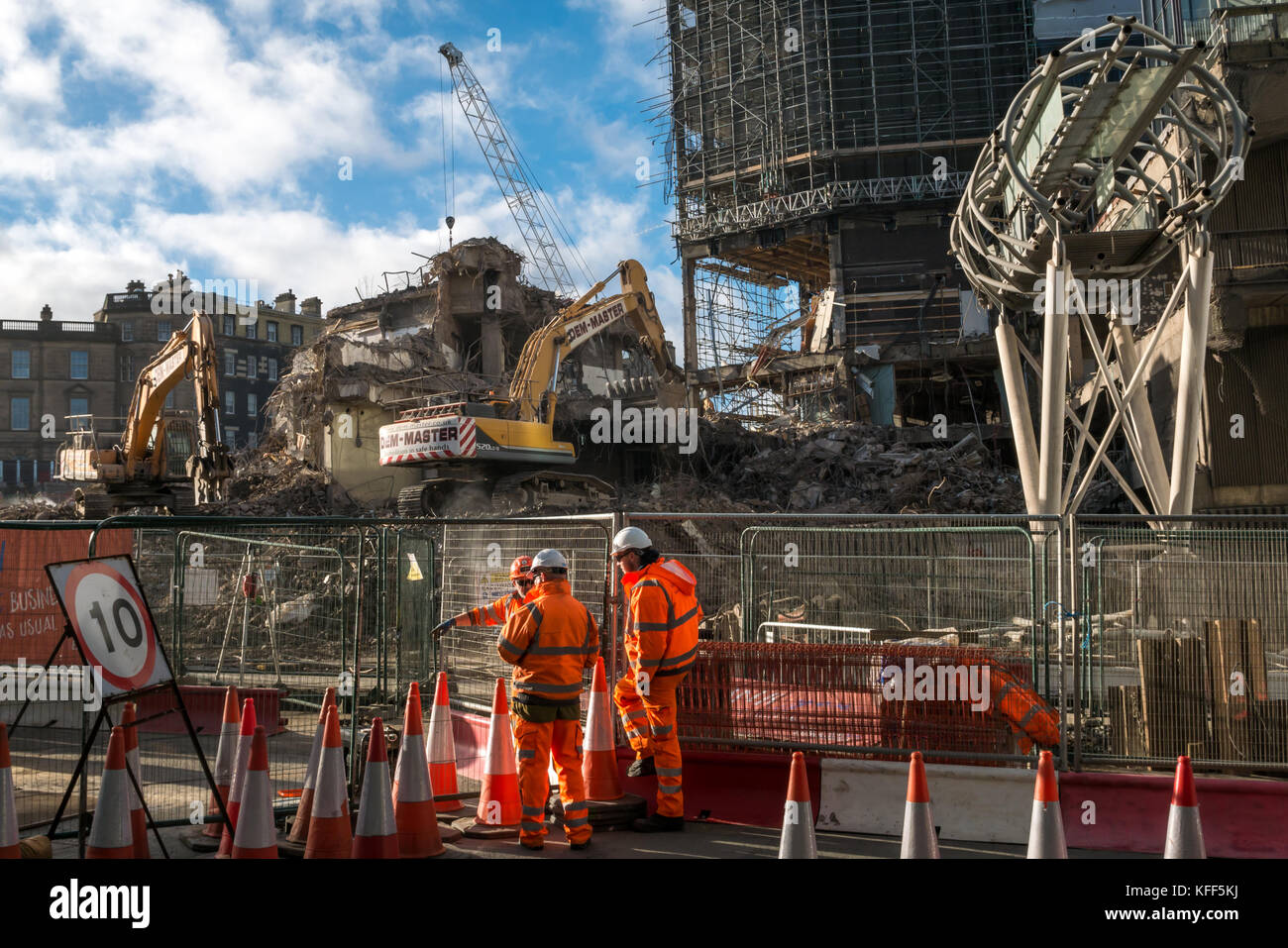 Demolition of 1970s St James Centre, Leith Street, Edinburgh, Scotland, UK, with workmen in orange in conversation on the building site Stock Photo