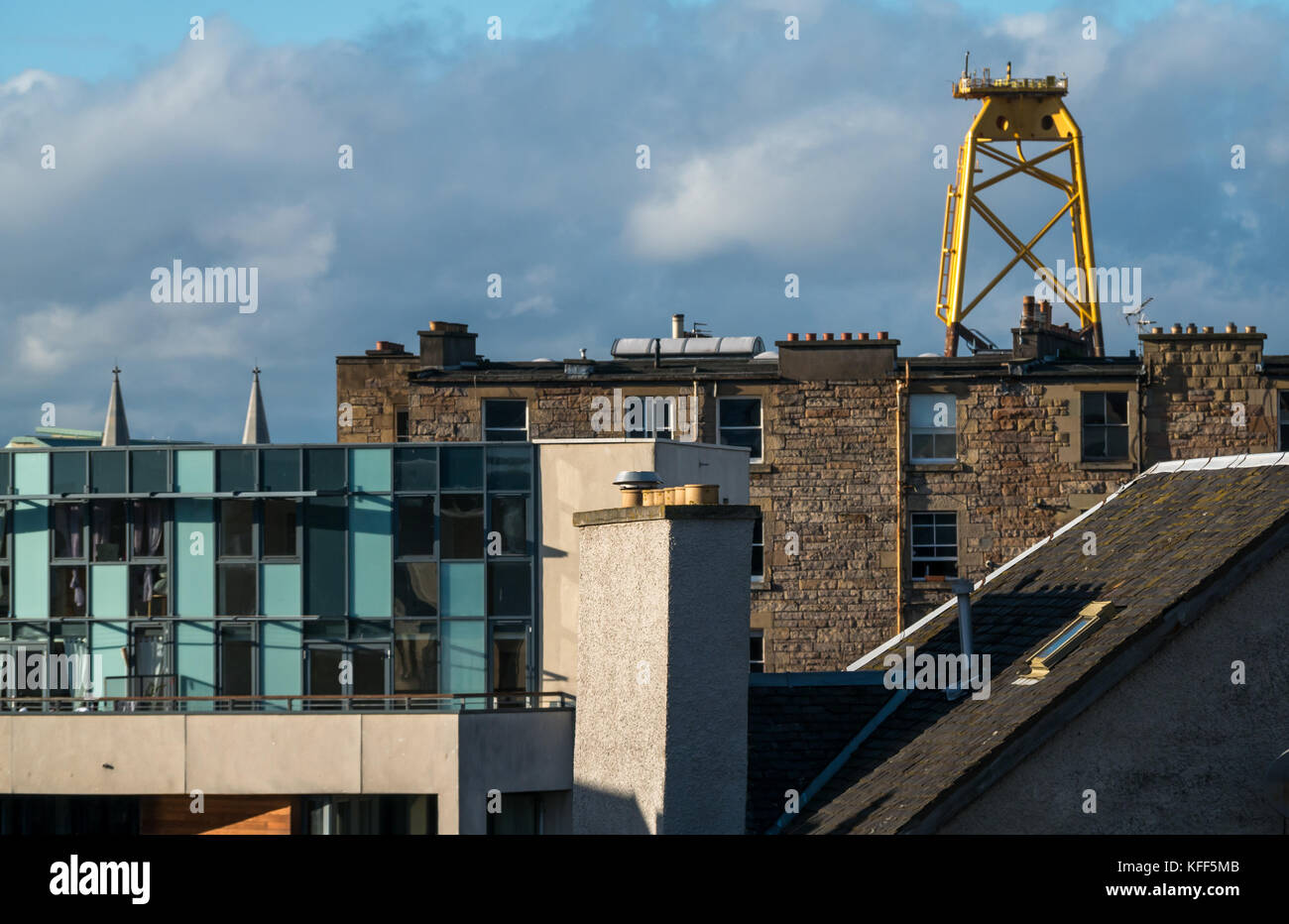 View over rooftops of old and modern buildings in Leith, Edinburgh, Scotland, UK, with huge yellow wind turbine platform in distance Stock Photo