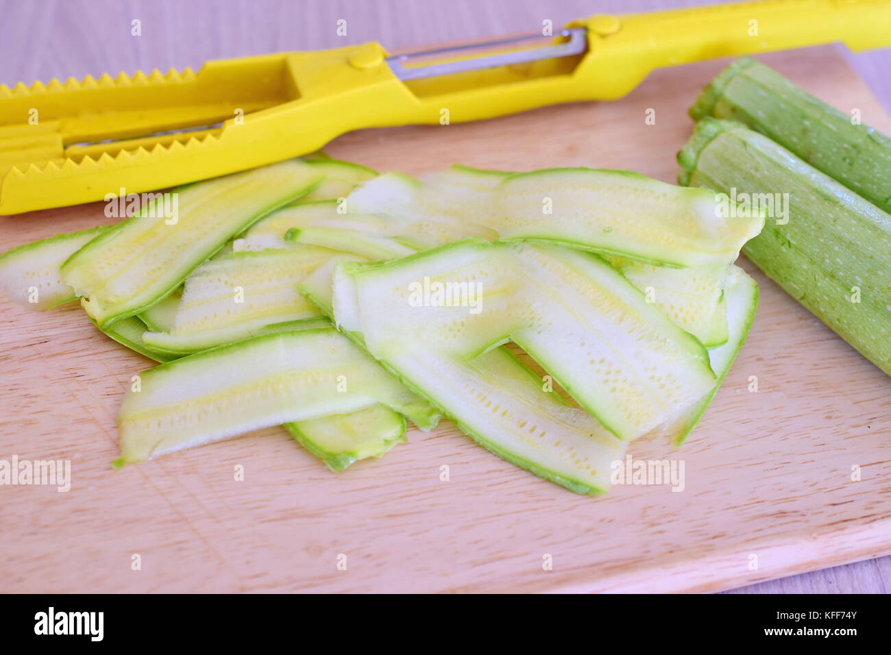 https://c8.alamy.com/comp/KFF74Y/fresh-zucchini-sliced-with-a-slicer-on-a-wooden-cutting-board-step-KFF74Y.jpg
