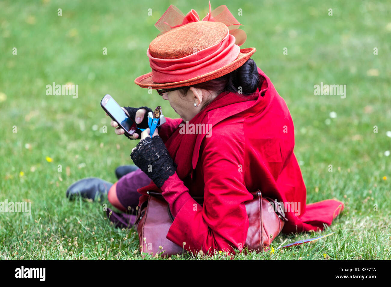 The senior woman dressed in red, uses her mobile phone, rear view Stock Photo