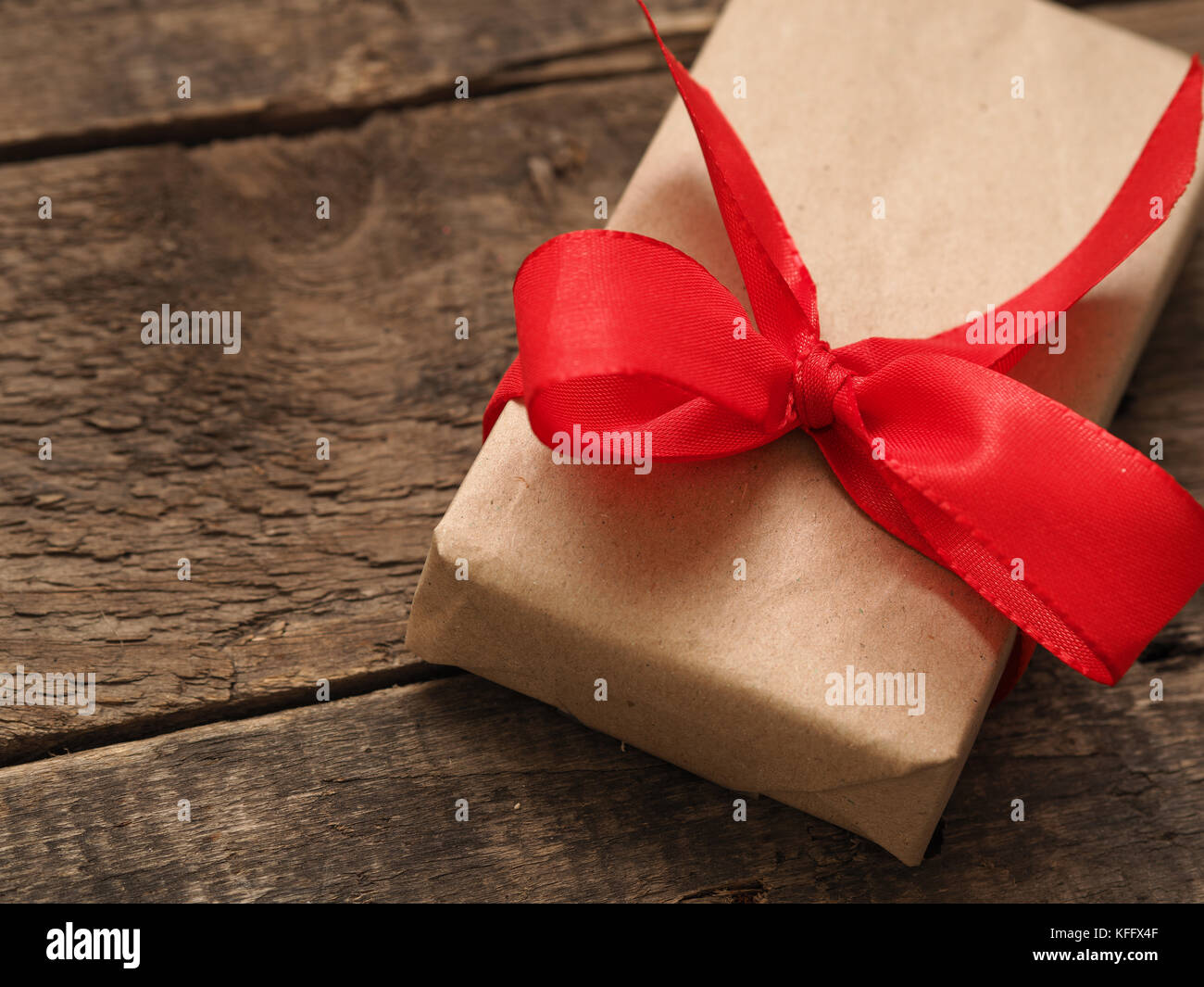 Gift box with a red bow on a rustic wooden background Stock Photo - Alamy